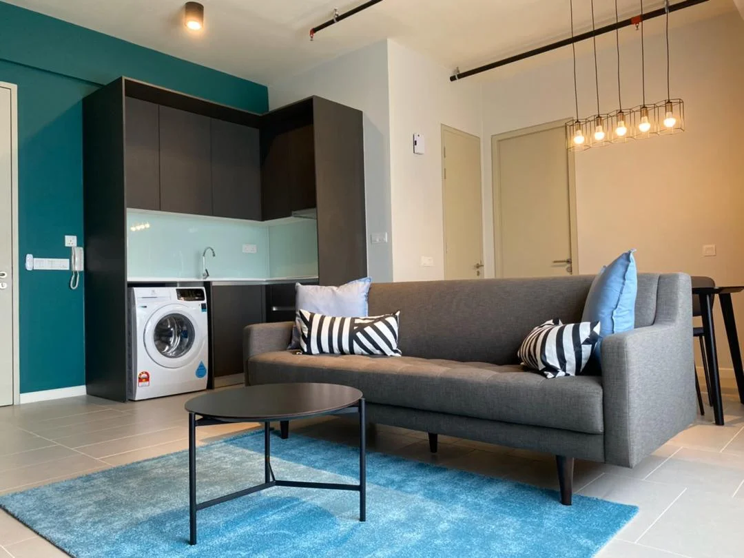 Living features: grey fabric sofa, black coffee table, blue area rug, wall-mounted washing machine, kitchenette with dark cabinetry, light green backsplash, stainless-steel sink, chrome faucet, pendant lighting with multiple bulbs, dining table with chairs, floor-to-ceiling windows, white walls, tile flooring; style: modern.